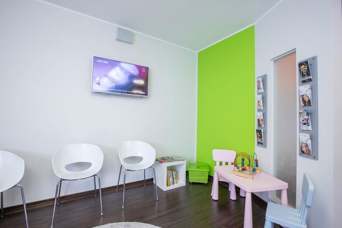 Ein Wartezimmer mit weißen Stühlen und einem rosa Tisch