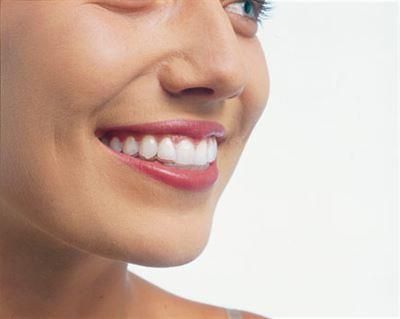 Eine Nahaufnahme des Lächelns einer Frau mit weißen Zähnen und rotem Lippenstift.