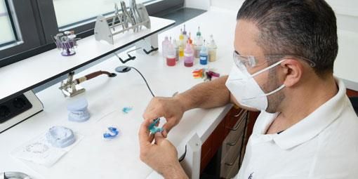 Ein Mann mit Maske und Brille arbeitet an einem Gerät.