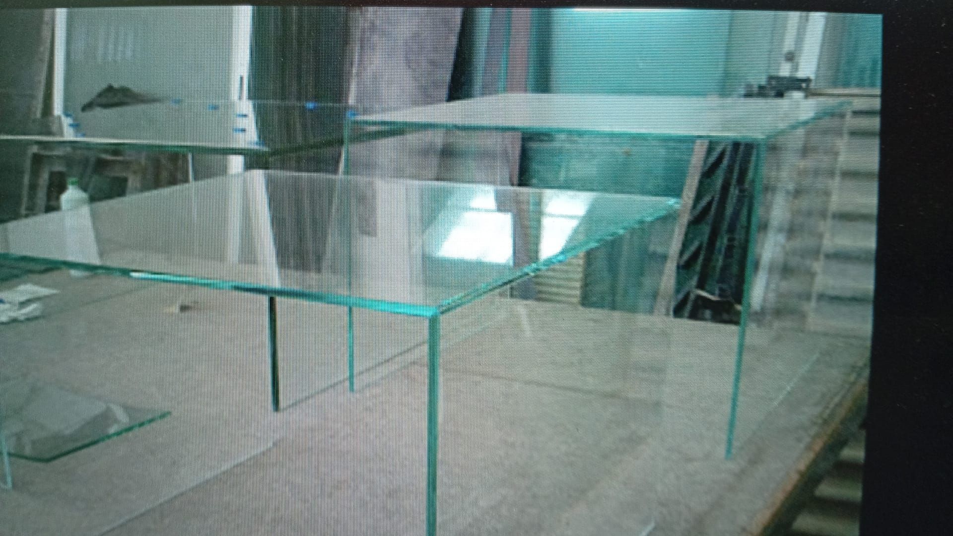 Mesas de cristal transparente con patas finas sobre superficie de madera.