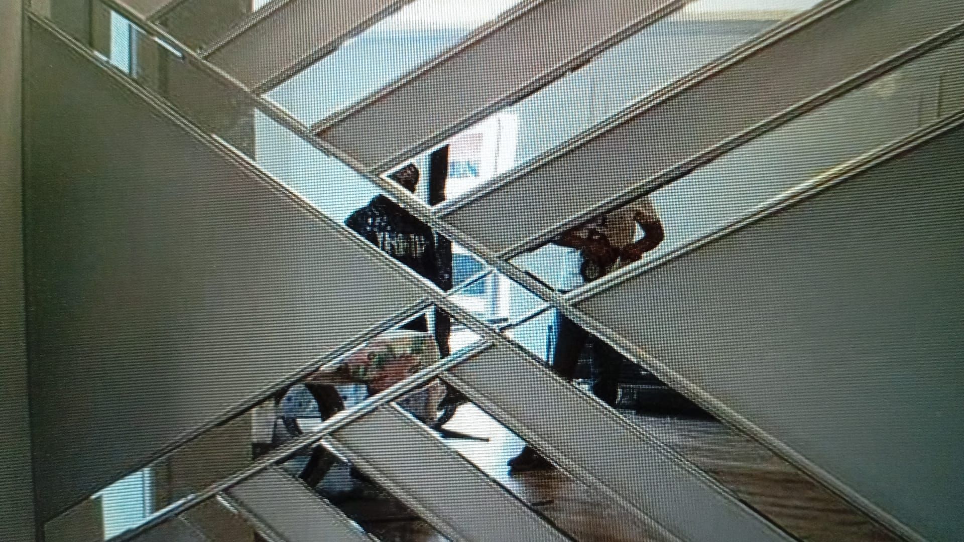 Diseño de pared con espejos que reflejan a personas en una habitación. Marcos plateados y patrón geométrico.