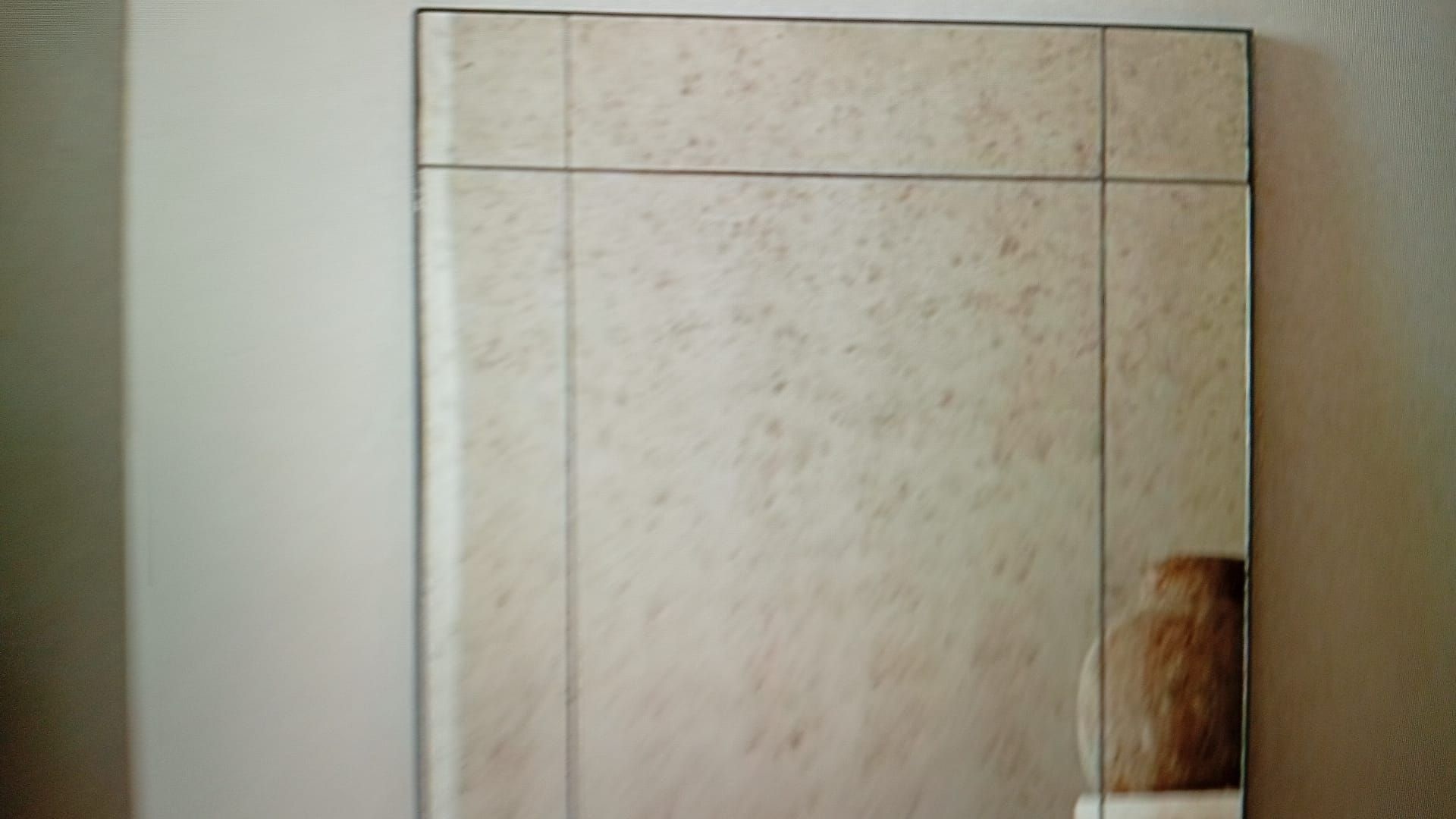 Espejo rectangular antiguo con acabado envejecido, colgado en una pared blanca.