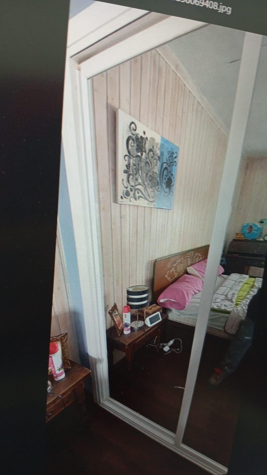 Interior de dormitorio con un gran armario con espejo, cama, mesita de noche y obras de arte.