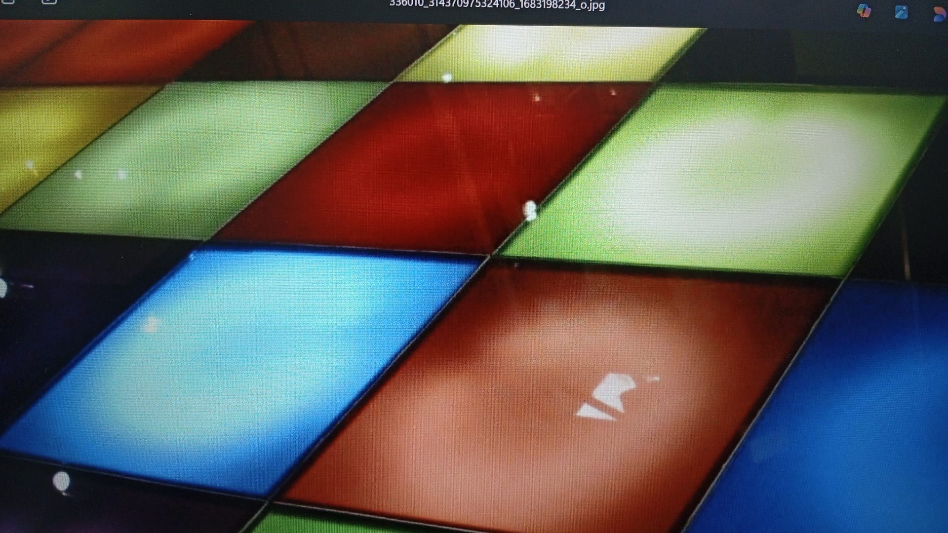 Fondo colorido con mosaicos diagonales. Cuadrados en tonos azules, verdes, rojos, marrones y dorados. Destellos de luz.