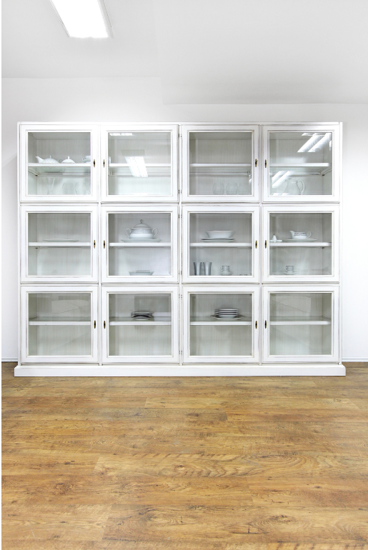 Vitrina blanca con puertas de cristal sobre suelo de madera.