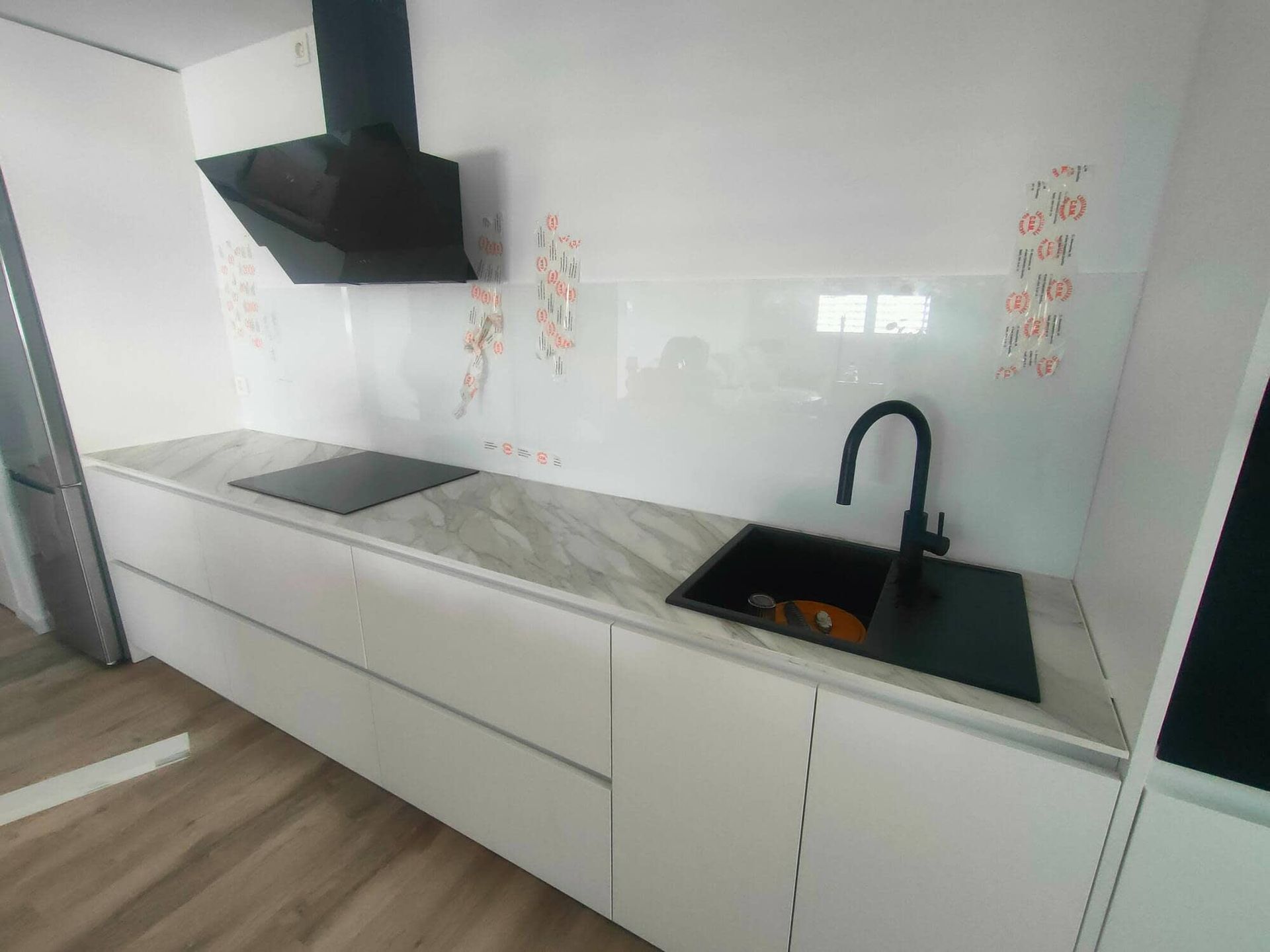 Mujer con mono azul pintando una pared blanca con un rodillo de pintura.