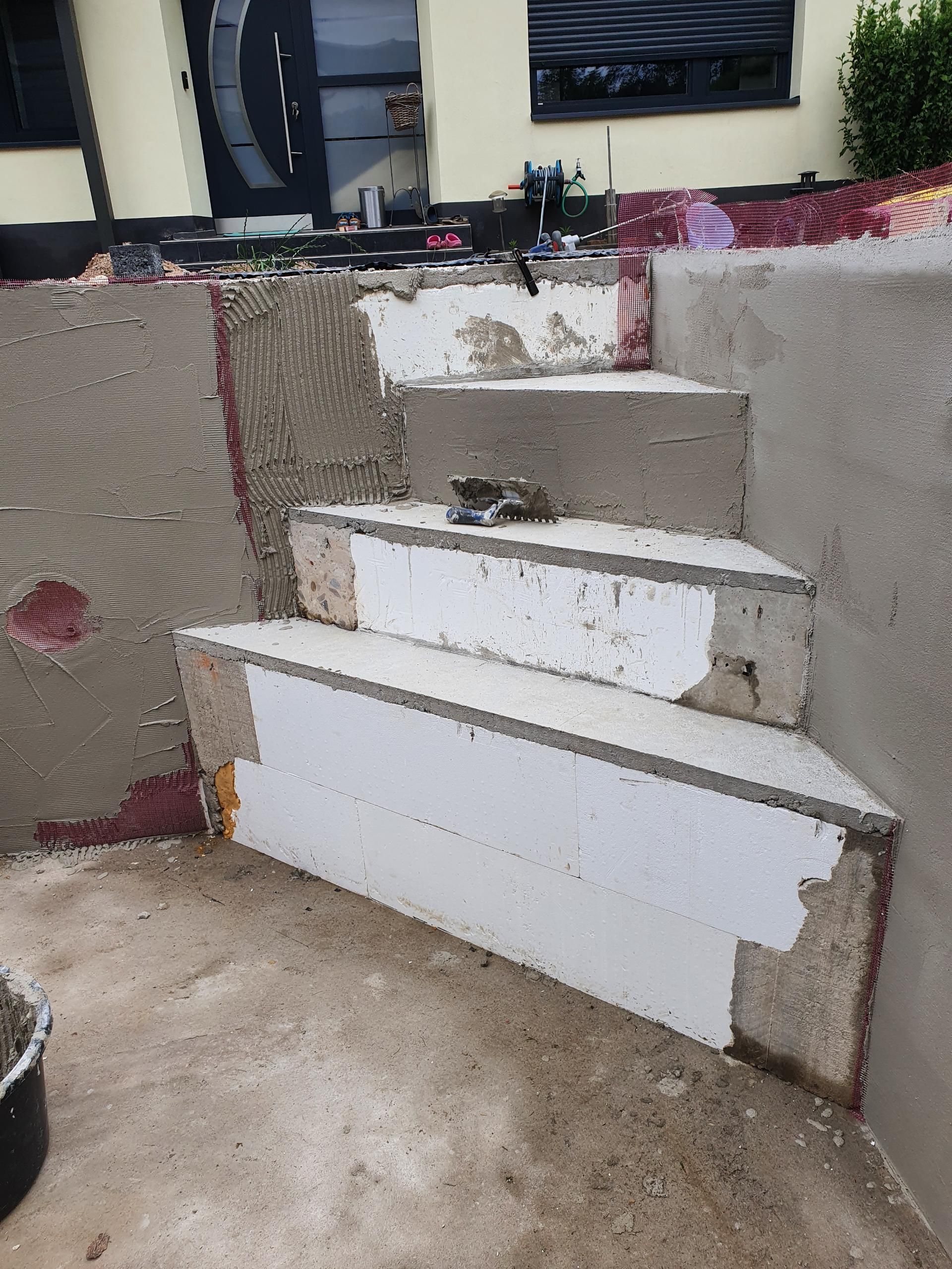 Im Bau befindliche Betontreppe mit freiliegendem Schaumstoff und Betonresten.