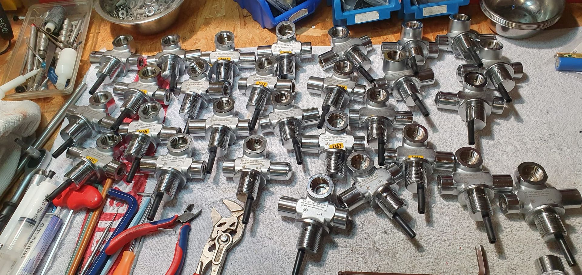 Eine Ansammlung von Metallventilen und Werkzeugen, die sich über eine Werkbank erstrecken.