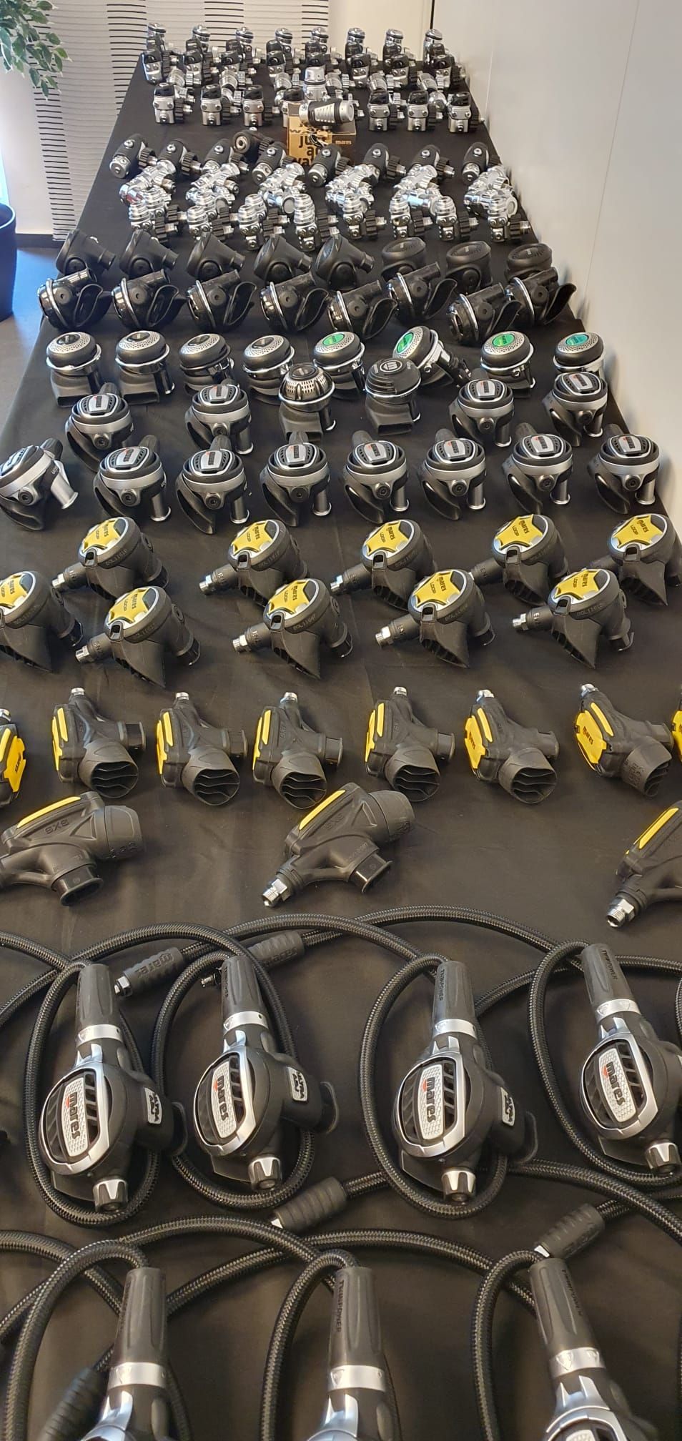 Auf einer schwarzen Fläche angeordnete Atemregler. Verschiedene Modelle von schwarzen und silbernen Atemreglern