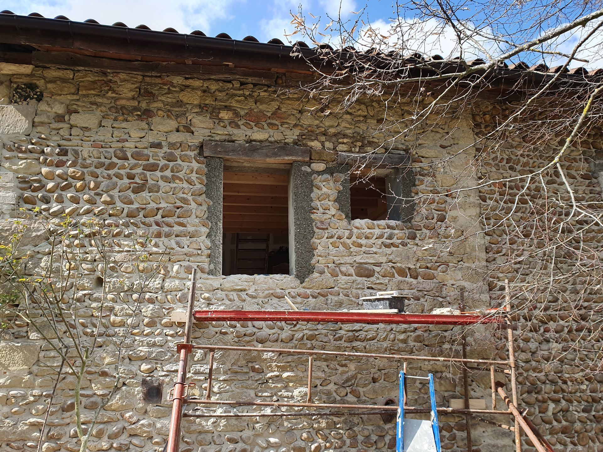 Rénovation avec un échafaudage devant un mur en pierres, travaux en cours