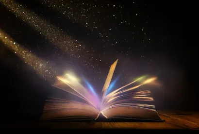 Libro abierto que brilla con luz de colores y destellos en un entorno oscuro.