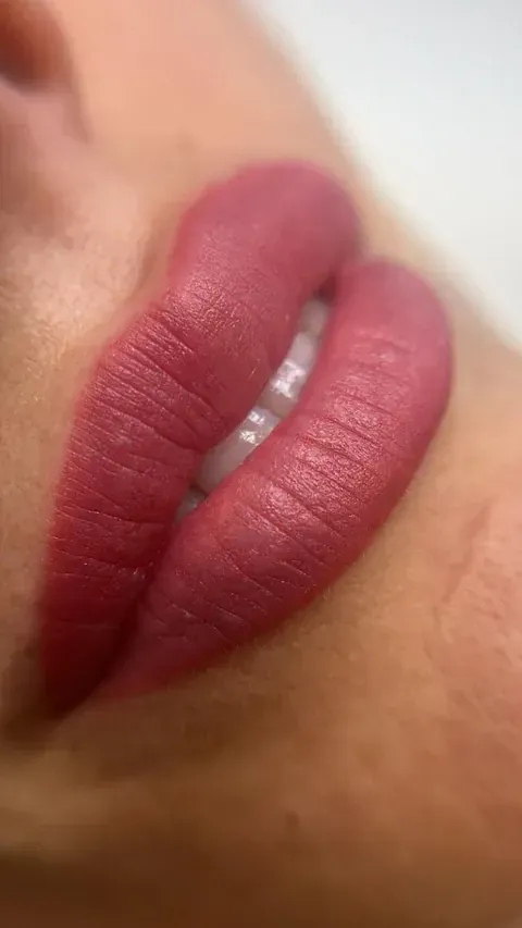 Un primer plano de los labios de una mujer con lápiz labial rosa.