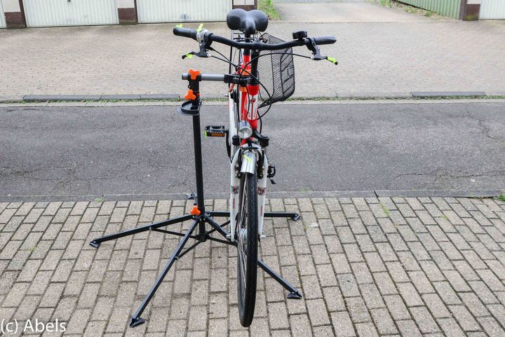 Ein Fahrrad steht auf einem Ständer auf einem gepflasterten Bürgersteig