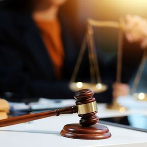 Le marteau du juge en premier plan avec une personne en arrière-plan.