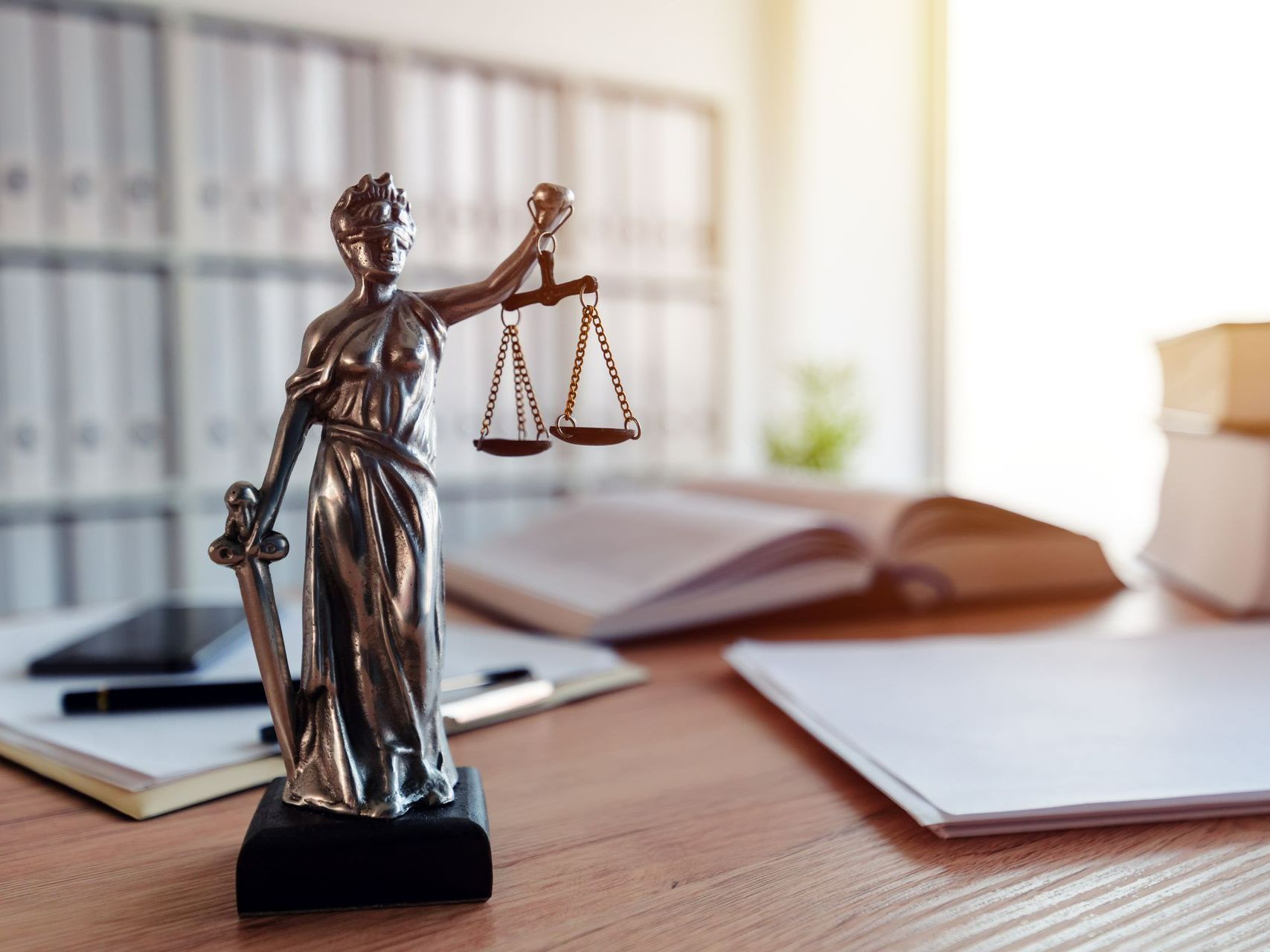 Statue de la justice avec des livres et des papiers en arrière-plan.