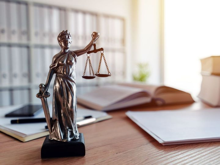 Statue de la justice avec des livres et des documents en arrière-plan.