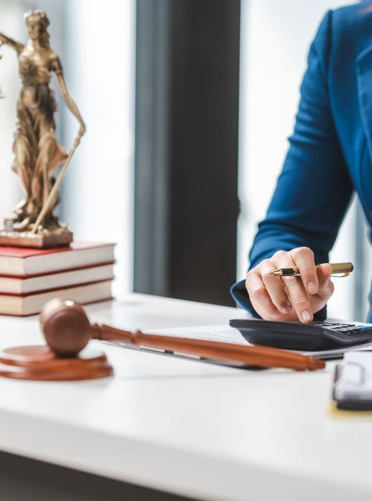 Une personne avec la calculatrice et le marteau de juge en premier plan.
