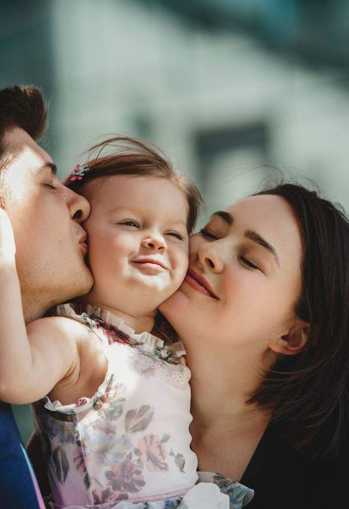 Parents et leur fille dans leurs bras.