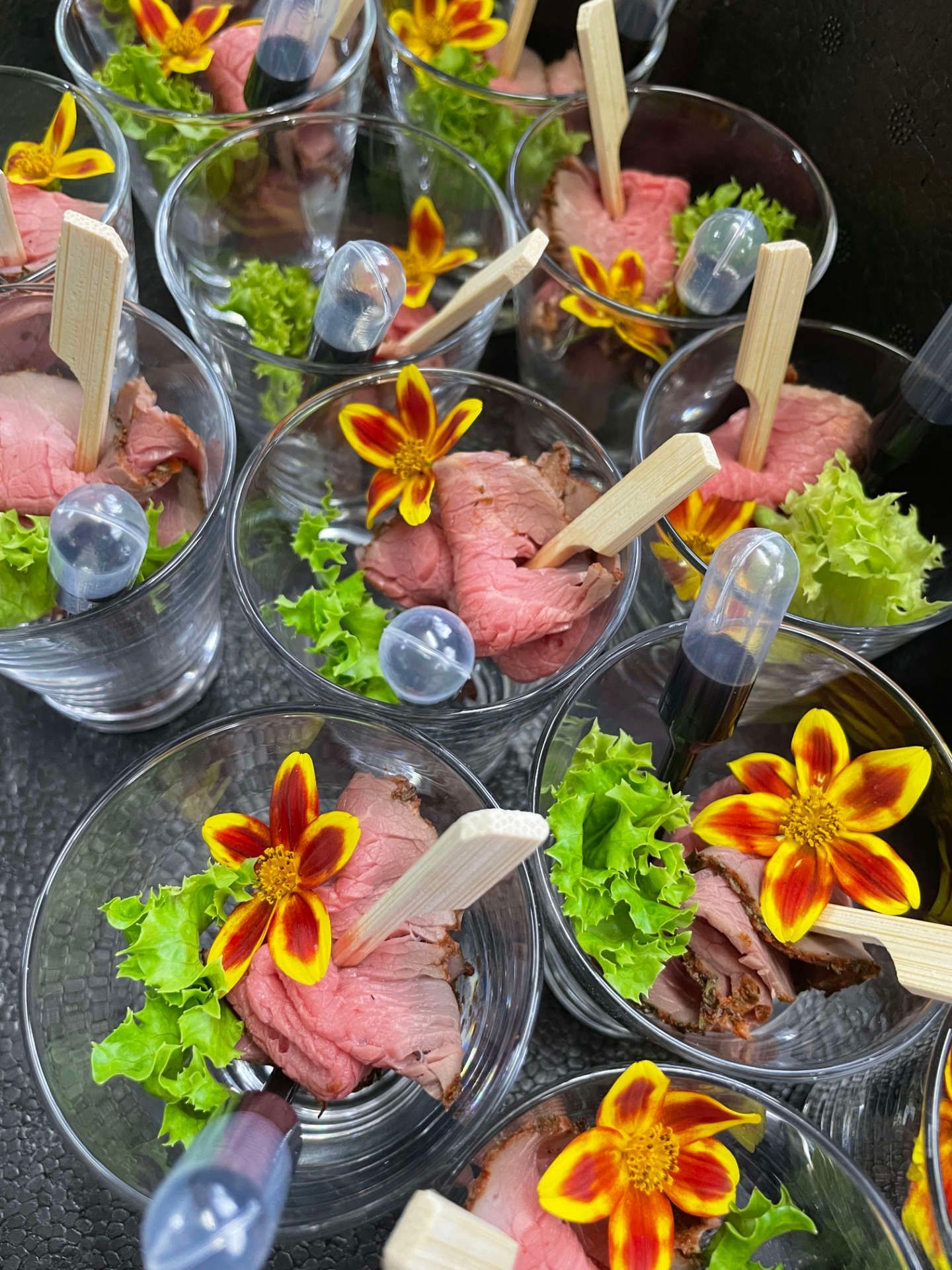 Ein paar mit Essen gefüllte Gläser und Blumen auf einem Tisch.