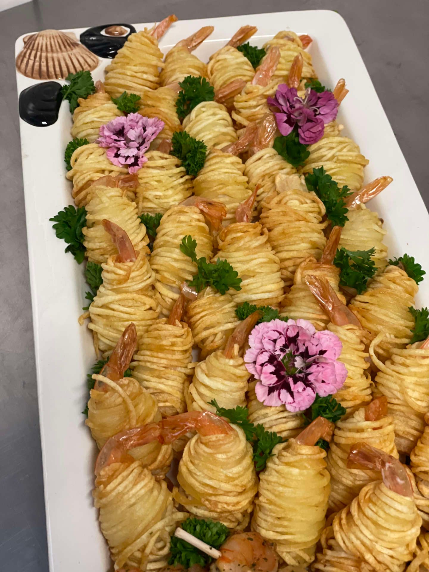 Ein weißer Teller mit in Garnelen und Blumen eingewickelten Nudeln.