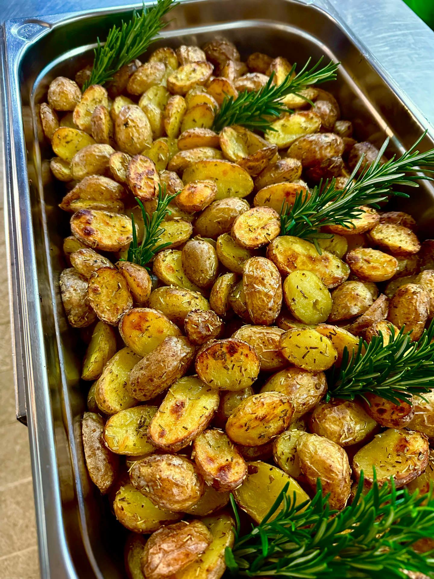 Ein Tablett mit Bratkartoffeln mit Rosmarin auf einem Tisch.