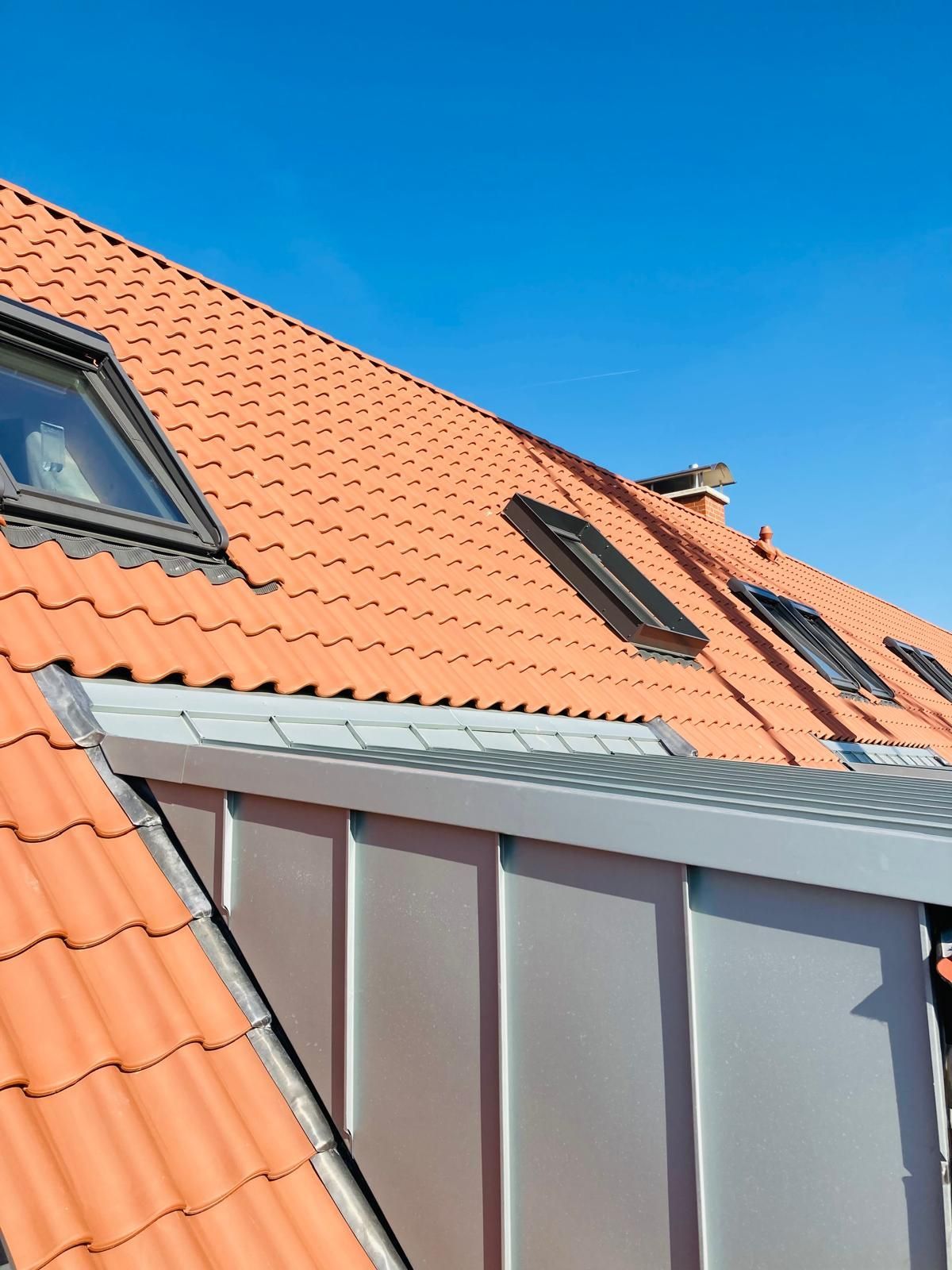 Ein rotes Ziegeldach mit einem blauen Himmel im Hintergrund