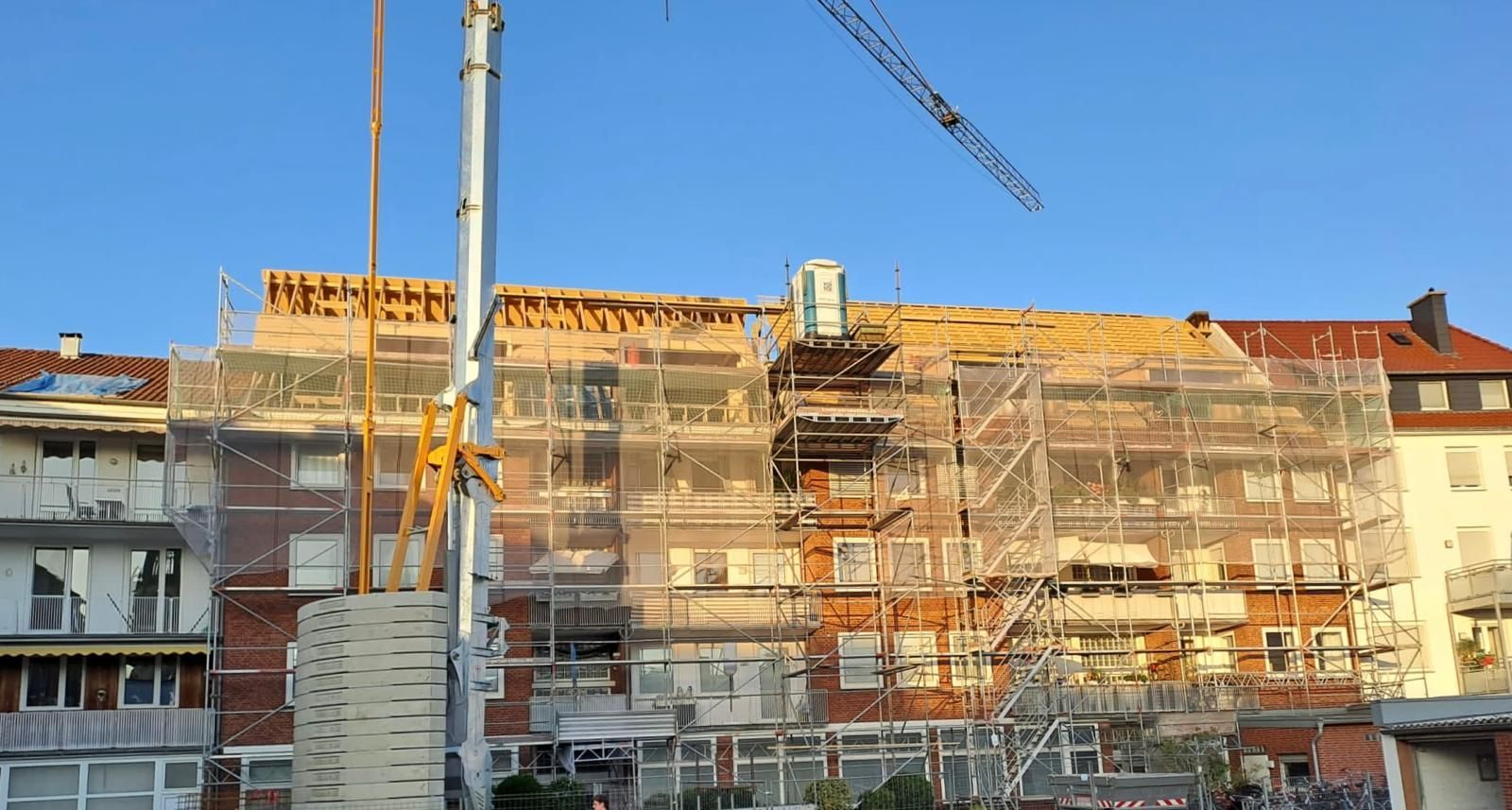 Mit Gerüst und Kran wird ein großes Gebäude errichtet.