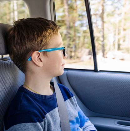 Un enfant roux avec des lunettes qui regarde par la fenêtre d'un taxi