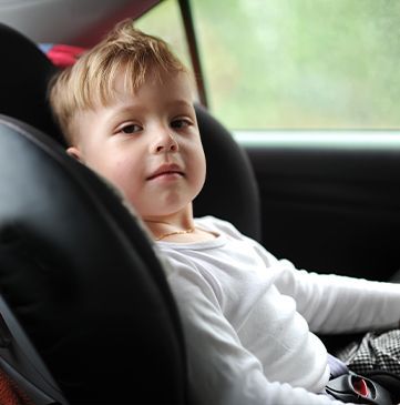 Un jeune enfant dans un siège auto regardant l'appareil
