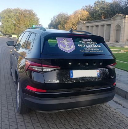Taxi de la marque Kadiac noir de dos à l'entrée d'un cimetière américain en Normandie