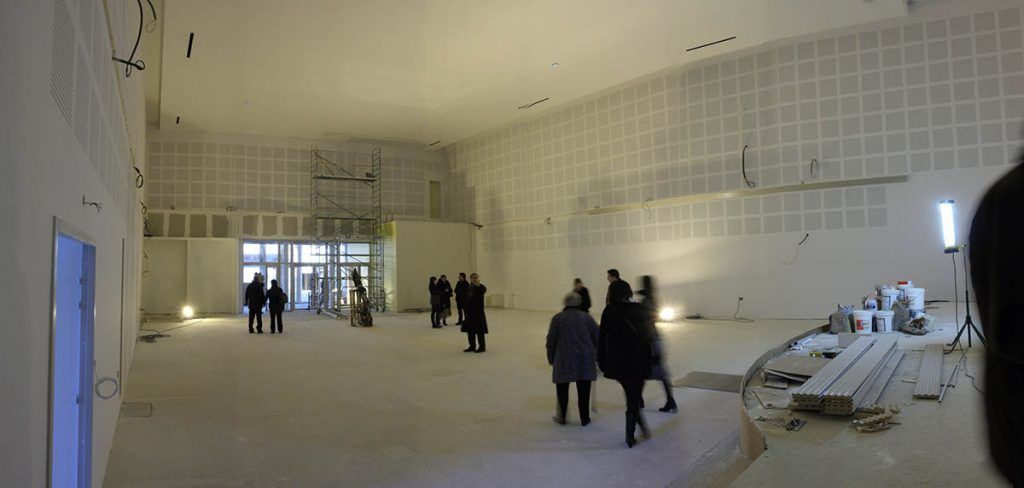 Des personnes dans une grande pièce blanche inachevée ; espace potentiel pour une galerie d'art.