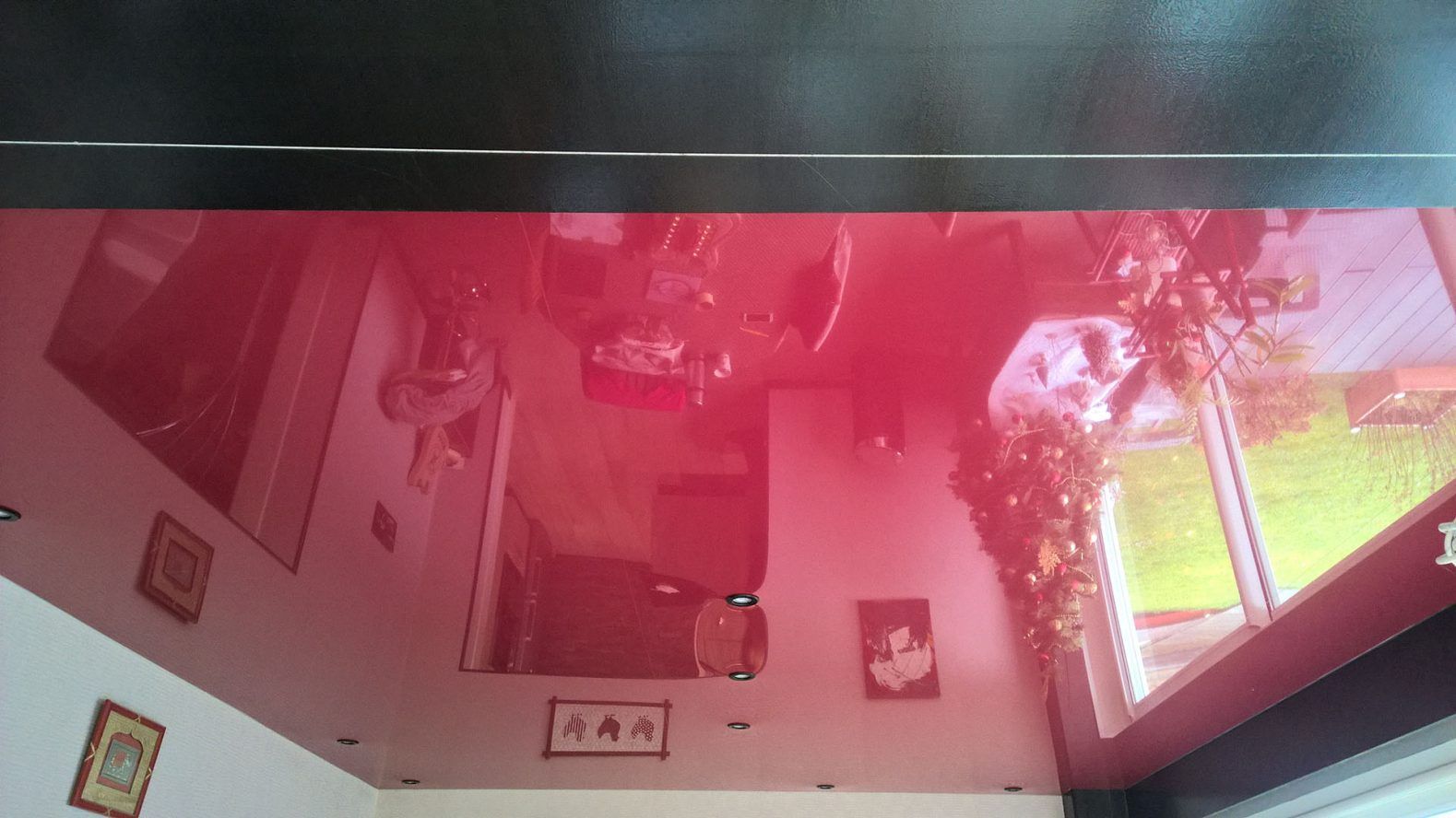 Plafond rouge réfléchissant avec reflet inversé de la pièce : fenêtres, tableaux, meubles.
