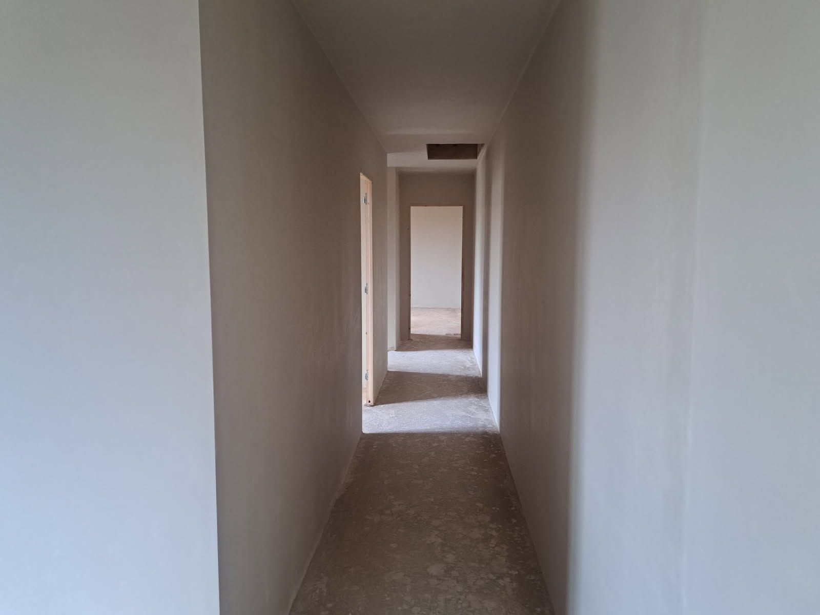 Couloir vide avec murs et portes blancs.