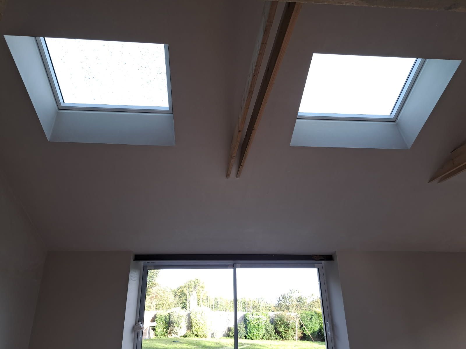 Deux puits de lumière et une grande fenêtre dans une pièce donnant sur une cour.