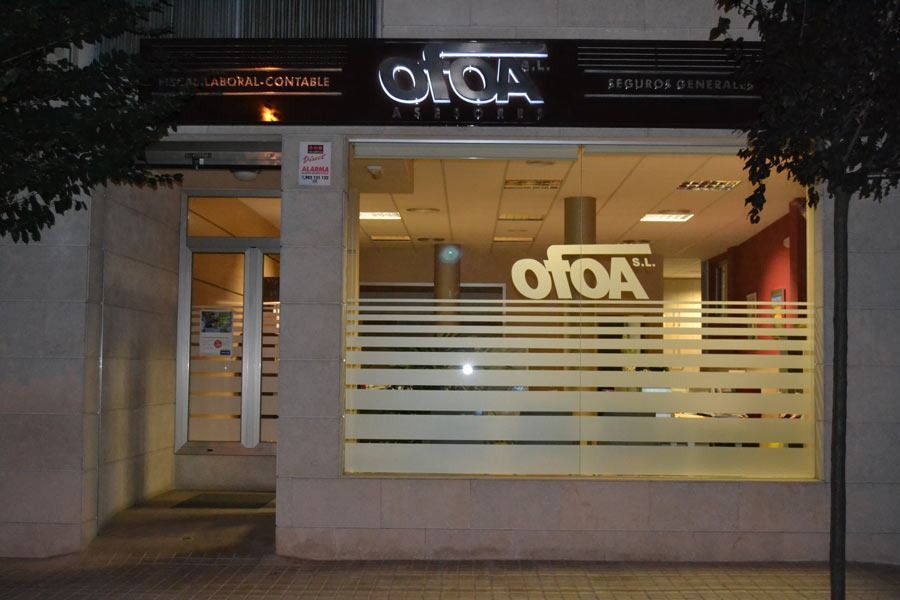 Exterior de la clínica OTOA de noche. Edificio iluminado con franjas esmeriladas en las ventanas, puerta de cristal y letrero encima.