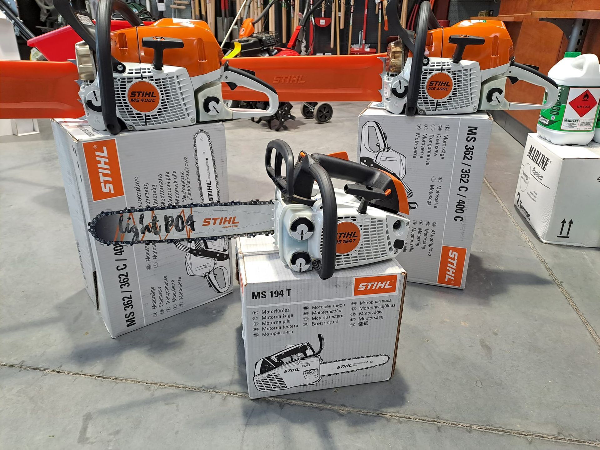 Des tronçonneuses Stihl neuves sur des cartons, à l'intérieur avec des outils en arrière-plan.
