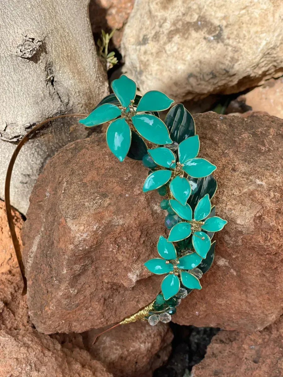 Diadema floral verde apoyada sobre una roca de color marrón rojizo.