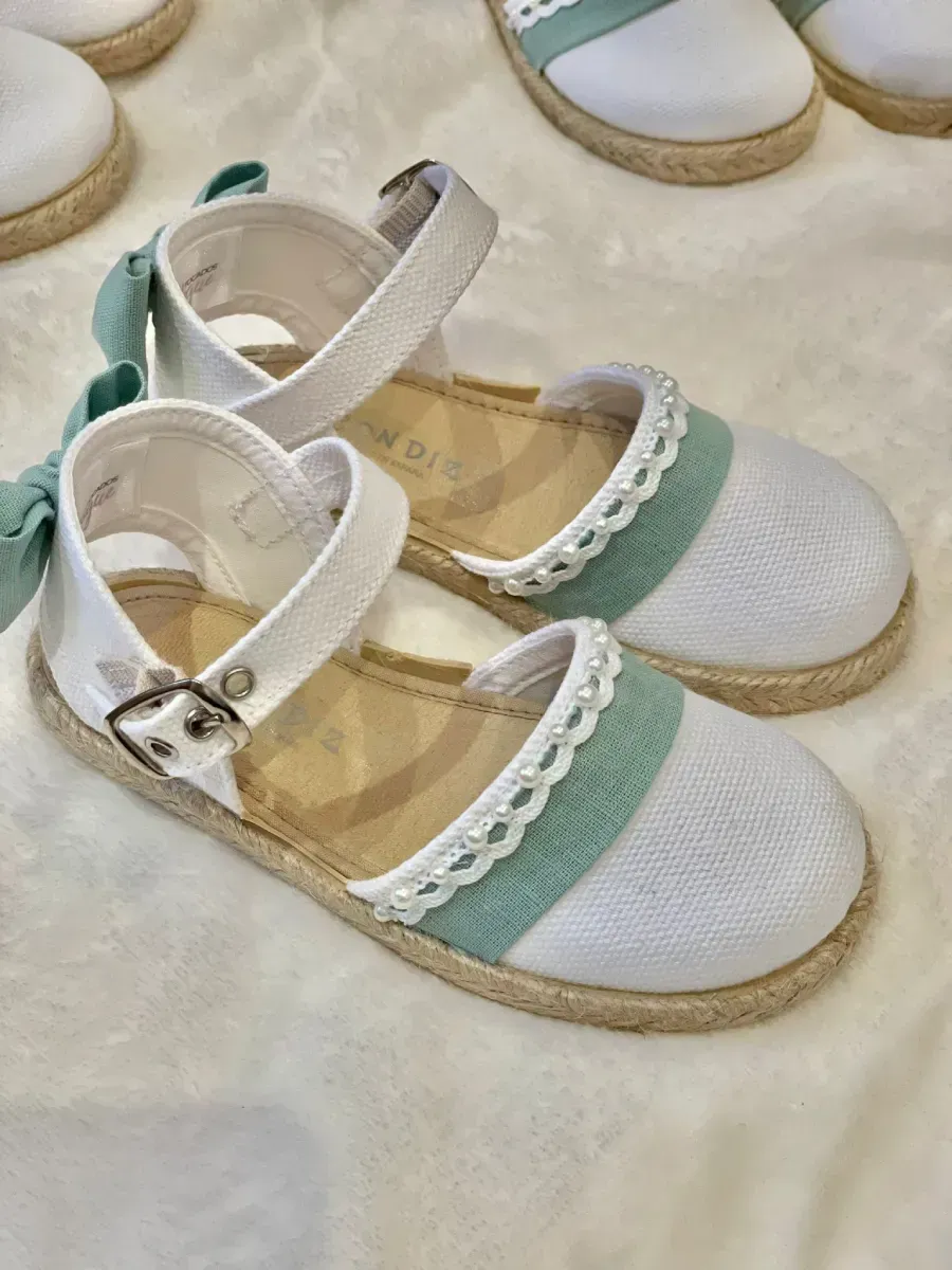 Sandalias de esparto en color blanco y verde menta con tiras en el tobillo y ribete de perlas.