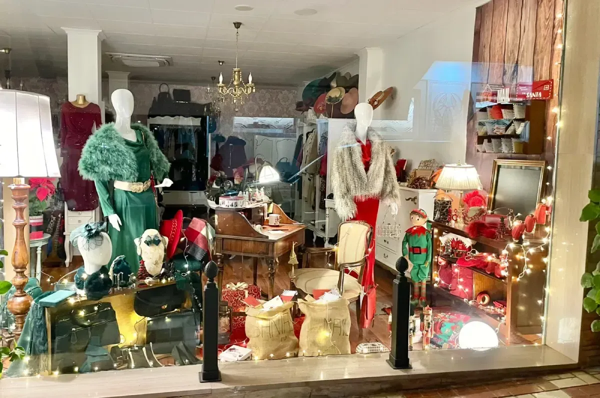 Escaparate de una tienda, con maniquíes vestidos de fiesta y elementos decorativos navideños.