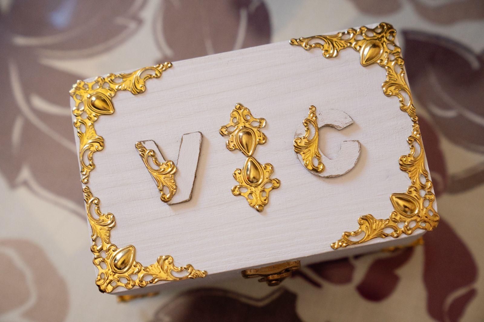 Caja blanca decorada con filigrana dorada e iniciales V & C.