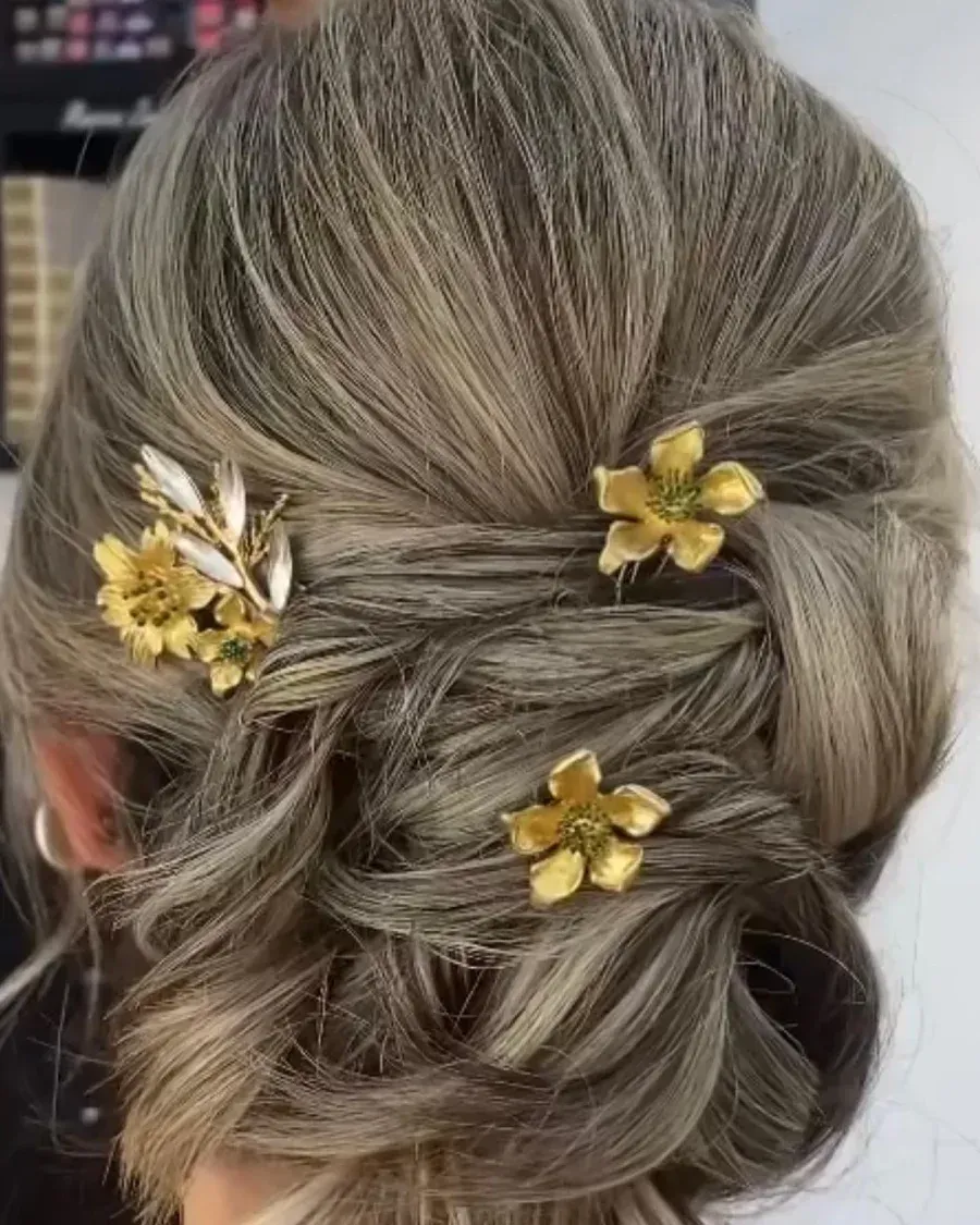 Peinado recogido con tres horquillas de flores doradas. Cabello gris y rubio, vista desde atrás.