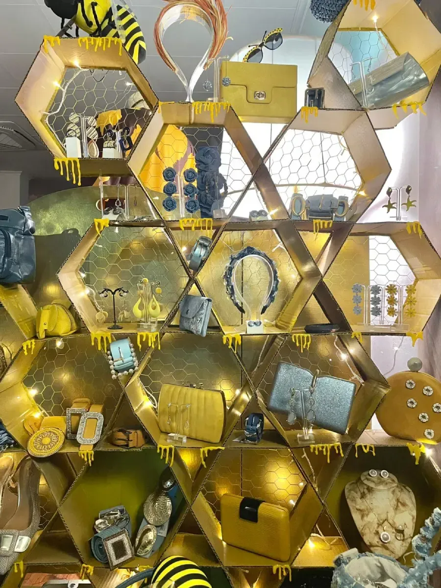 Expositor de joyas y accesorios en forma de panal, en tonos dorados y amarillos, con temática de abejas y miel.