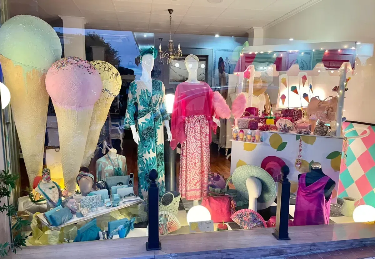 Un escaparate con conos de helado gigantes y maniquíes con ropa y accesorios coloridos.