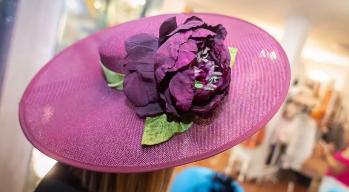 Sombrero rosa con flor morada y hojas verdes.