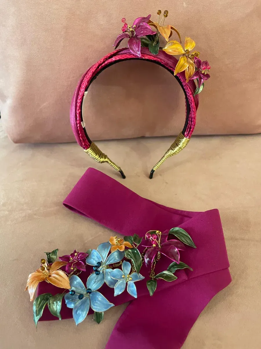Diadema y fajín de color rosa adornados con detalles florales coloridos.