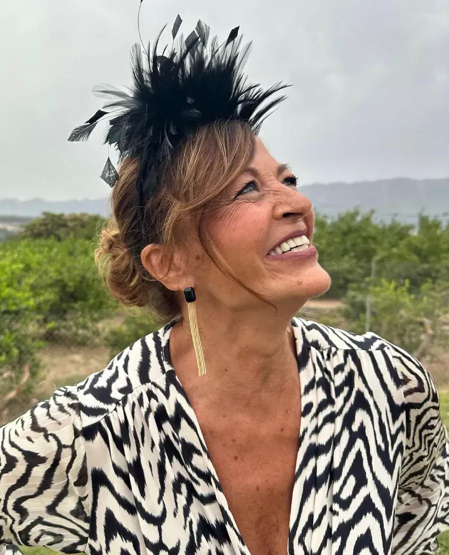 Una mujer con una camisa con estampado de cebra, un tocado de plumas negras y pendientes dorados