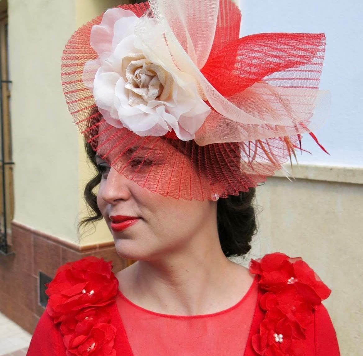 Mujer con vestido rojo y sombrero adornado de color rojo/crema con velo.