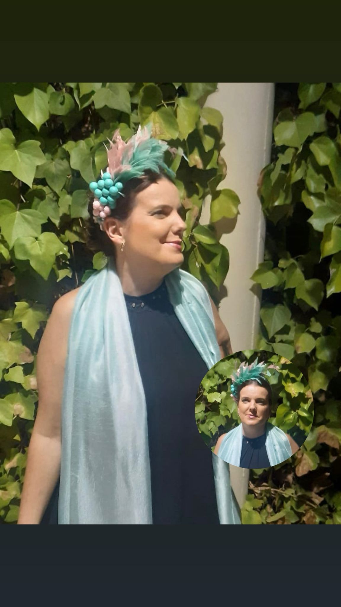 Mujer con tocado y chal color verde azulado, sonriendo, posando delante de la hiedra.