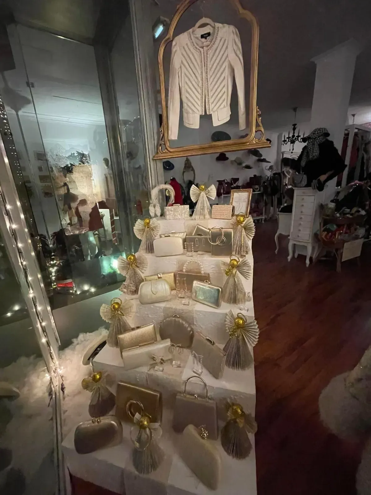 Un escaparate con bolsos y una chaqueta, decorado con figuras de ángeles y luces.