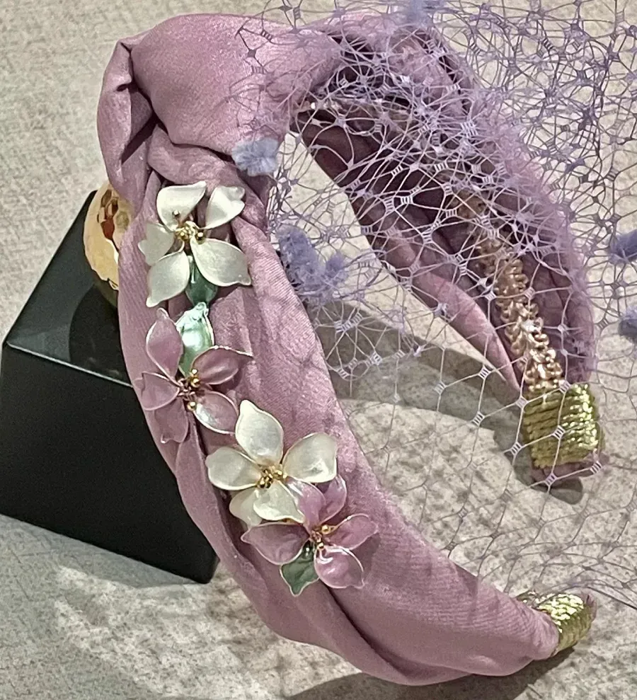 Diadema de tela lavanda con adornos florales y velo.